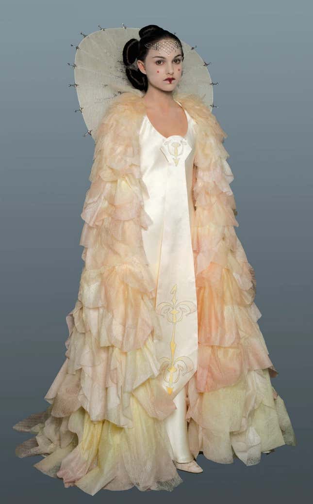Padme stands in her costume from the parade on Naboo, all covered in pink and white ruffles. 